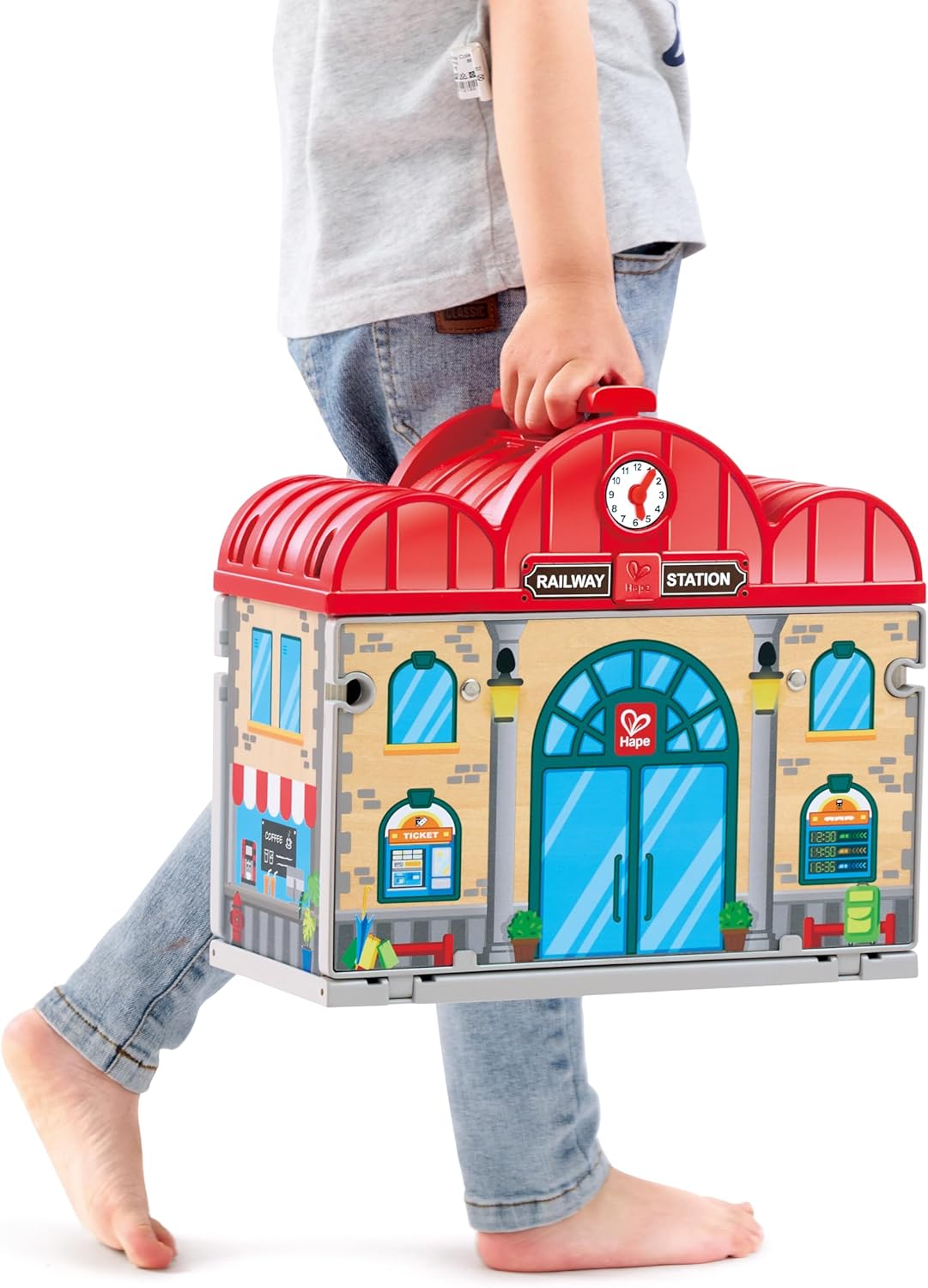 Child holding a toy train station set against a white background