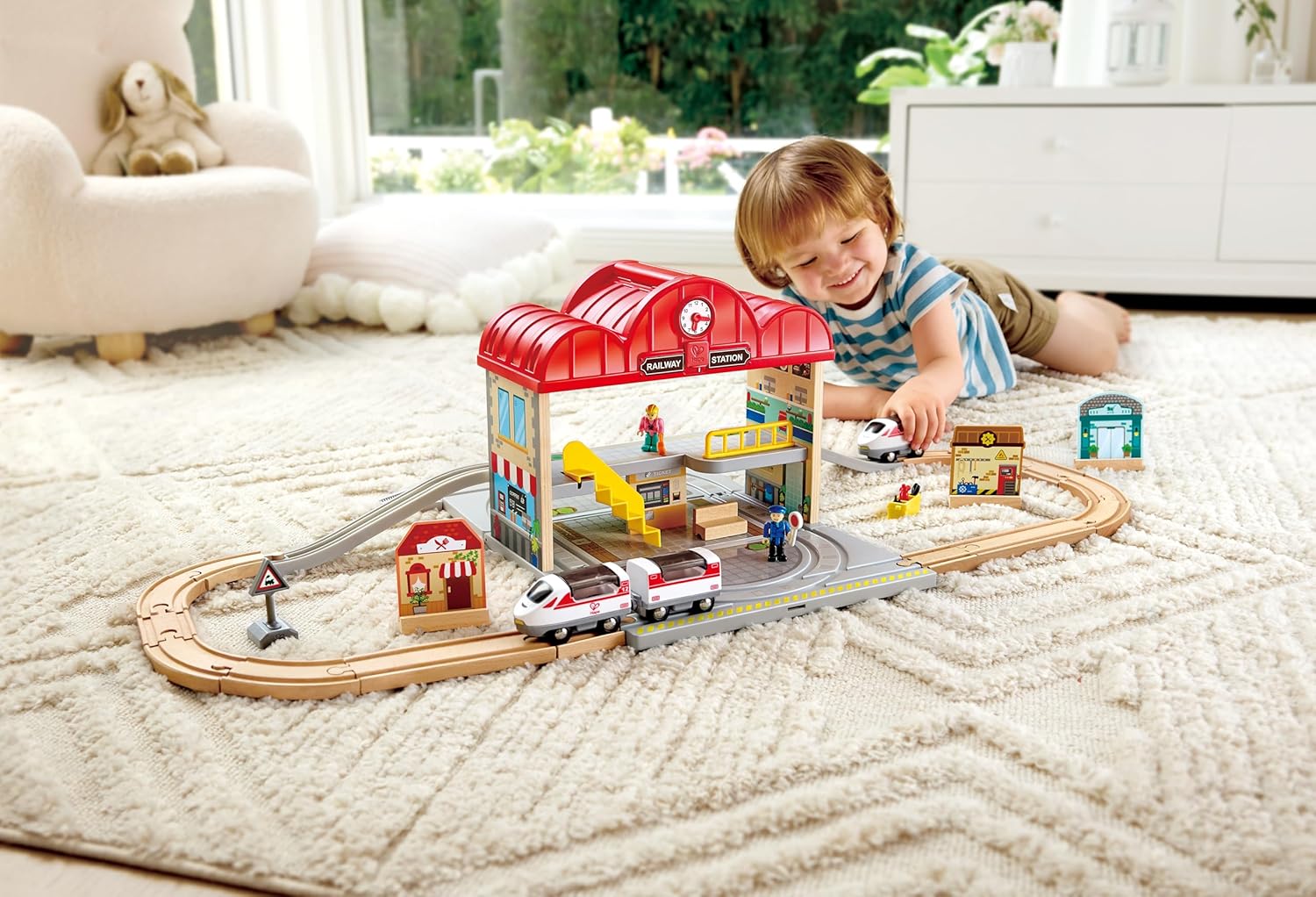 Child playing with a toy train set in a living room