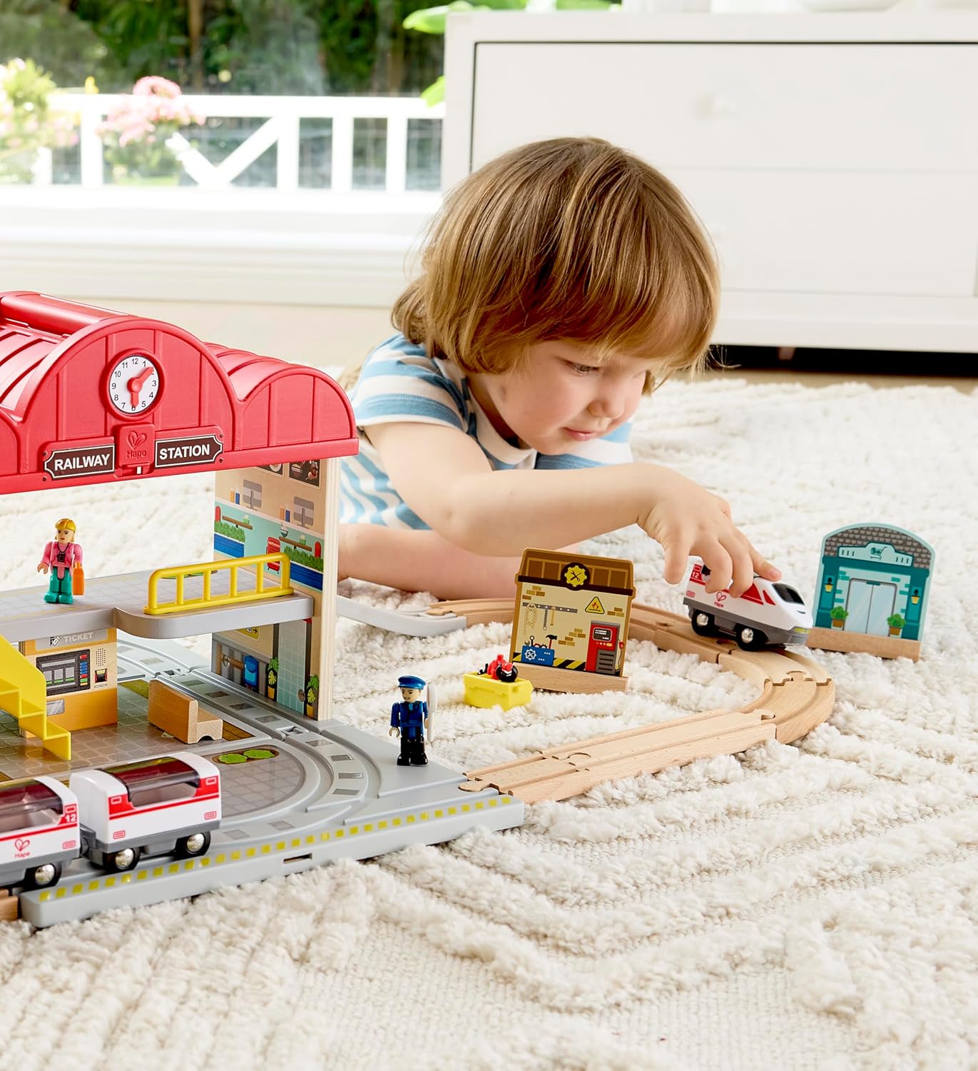 Child playing with a toy train set on a carpeted floor