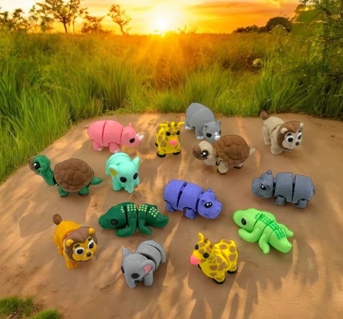 A collection of colorful, animal-shaped toy figures printed with a 3D printer, set outdoors with a sunset in the background.